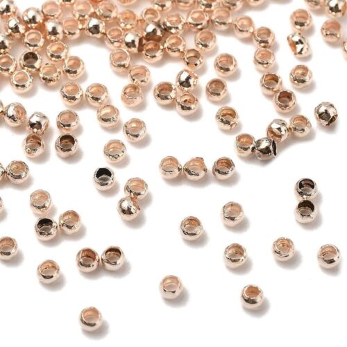 Rose gold round crimp beads 2mm warm blush rose gold plating open barrel shown bulk scattered close-up and ruler scale jewellery making Australia