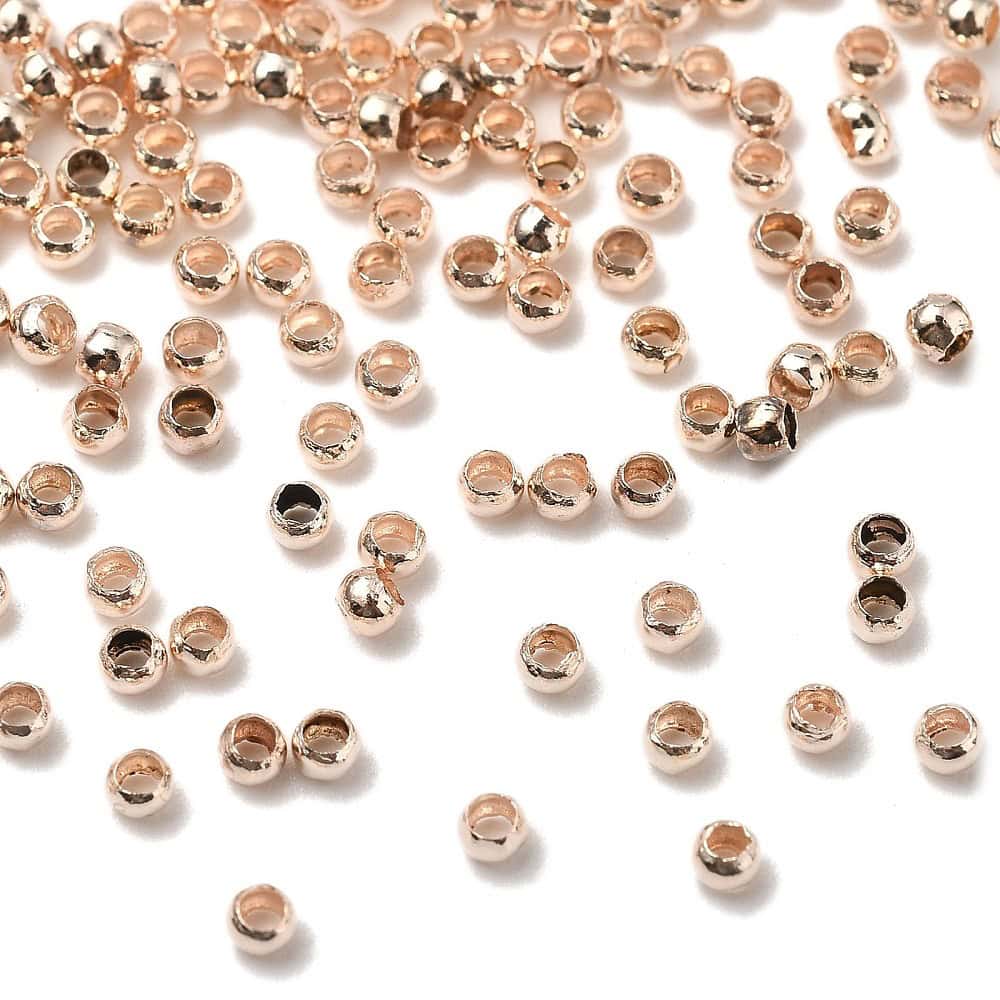 Rose gold round crimp beads 2mm warm blush rose gold plating open barrel shown bulk scattered close-up and ruler scale jewellery making Australia
