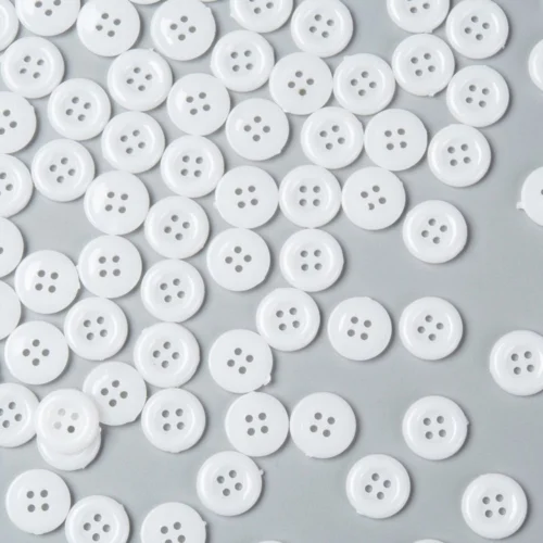 White acrylic 4 hole costume design buttons glossy finish raised rim scattered on grey background craft sewing Australia